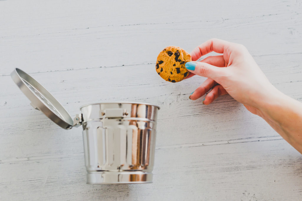 Eine Hand schmeißt einen Keks in einen Mülleimer – ein Sinnbild für Google, das die Third Party Cookies abschafft.