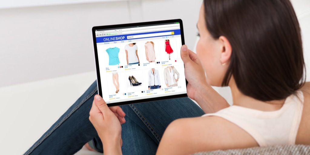 Eine junge Frau surft mit dem Tablet auf einem Online-Shop.