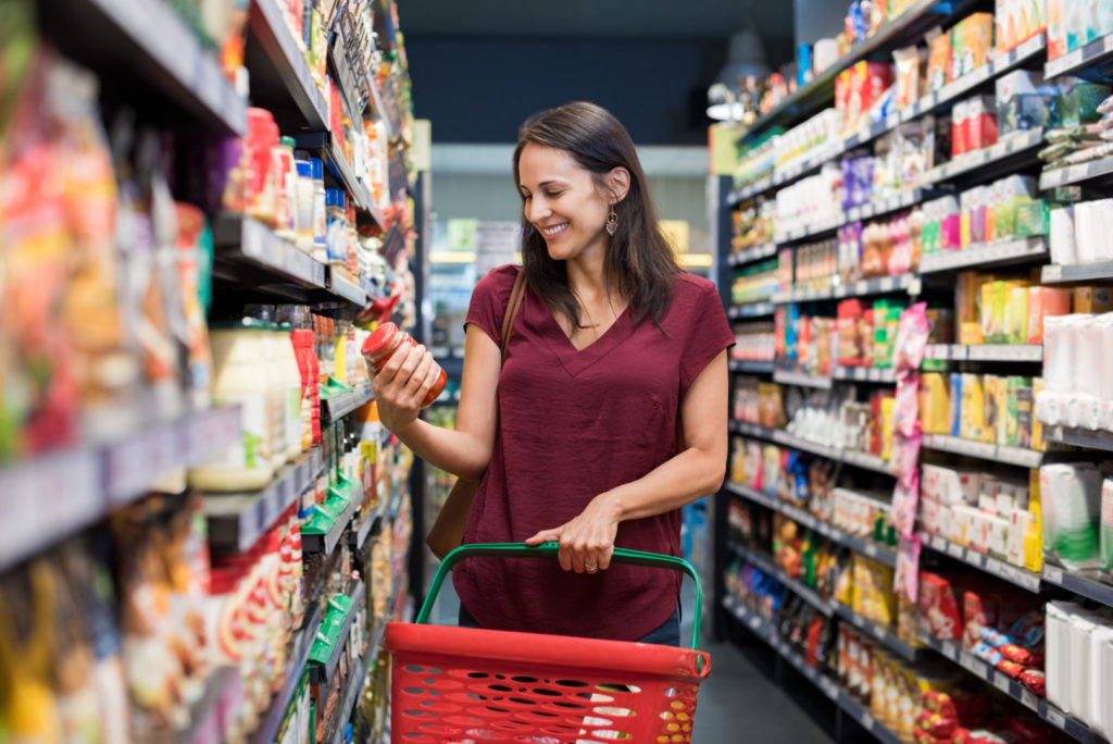 Eine Frau mittleren Alters findet die gewünschten Produkte problemlos innerhalb des Supermarkt-Regals.