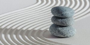 Drei Steine gestapelt in einem Zen-Garten als Sinnbild für das Triumvirat des Designs nach Tom Moog: Ordnung, Kontrast, Reduktion.