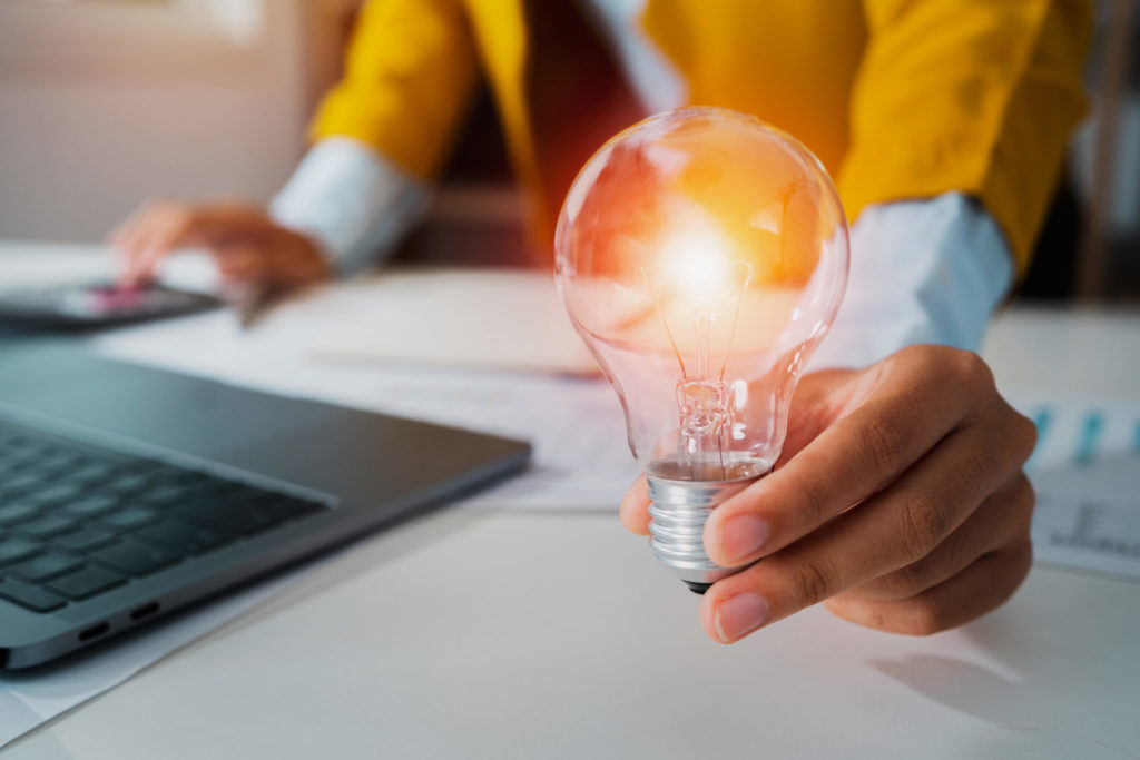 Eine Online-Marketing-Angestellte hält eine Glühbirne als Symbol für nützlichen Content, der vom Helpful Content Update gefördert wird.