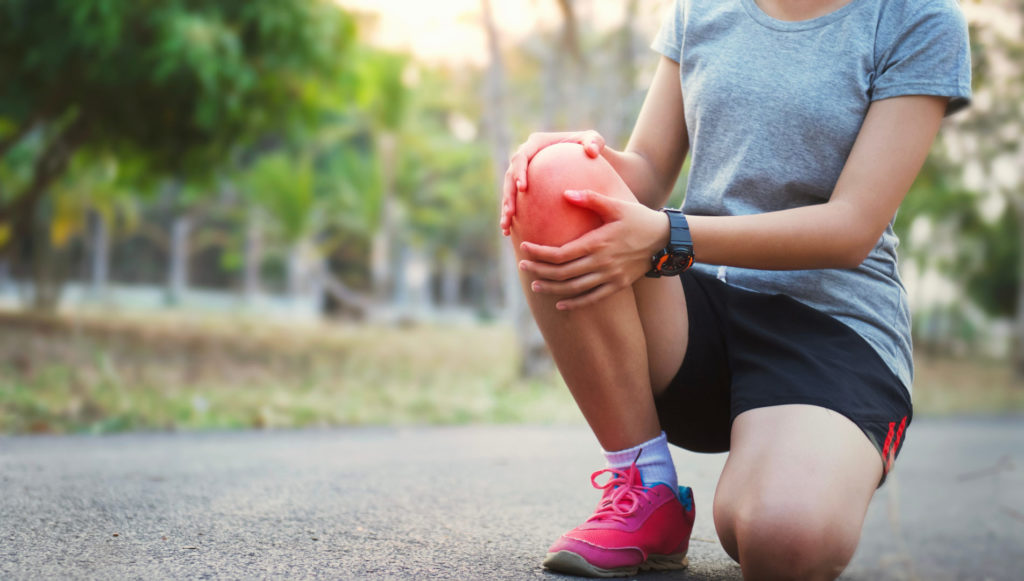 Eine Joggerin hält sich das Knie, weil sie Schmerzen vom Laufen bekommt – unser Customer Journey Beispiel.