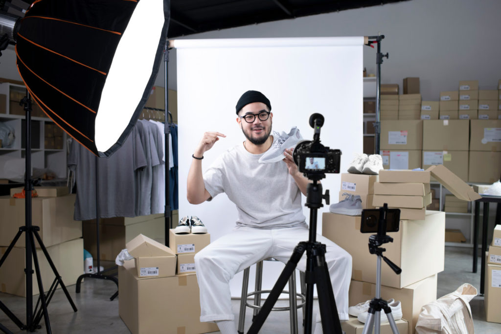 Ein Social-Media-Influencer präsentiert Sneakers vor der Kamera in seinem Heimstudio. 