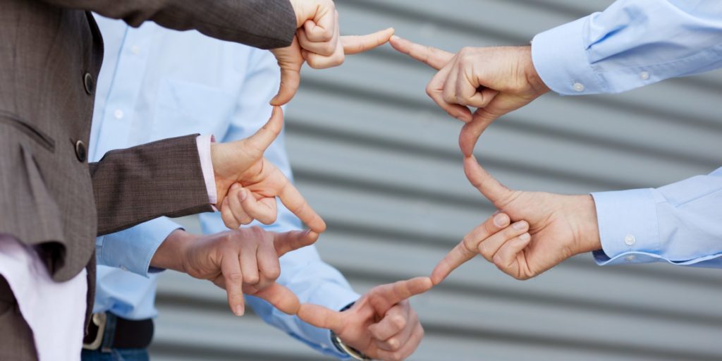 Mehrere Online-Marketer verbinden ihre Finger zu einem Netz. Ein Symbolbild für den Linkaufbau zwischen Unternehmen.